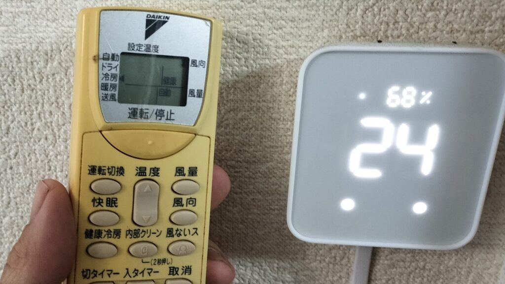 SwitchBotハブ2とエアコンのリモコンの画像です